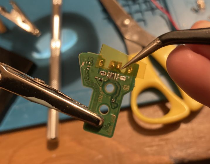 The dualshock power PCB with the Micro USB port ripped off. You can see five tiny contacts, two of which are shorted with solder.