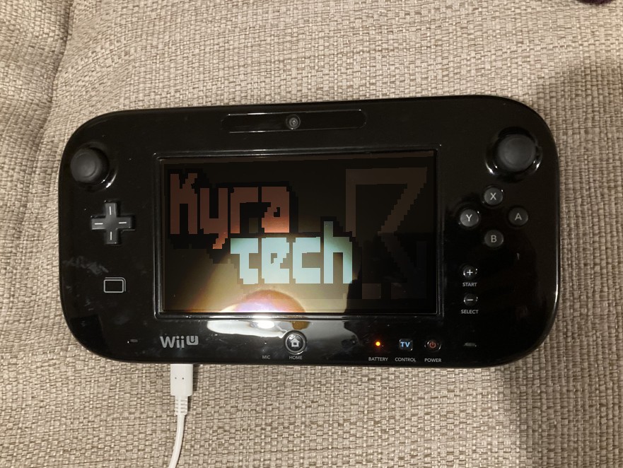 A Wii U game pad plugged in and charging using a generic USB-C cable. The cable connects to the bottom left of the pad.